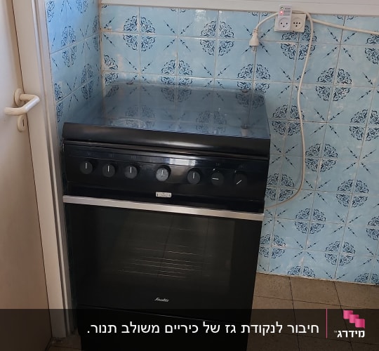 תנור שחור עם כפתורים במטבח עם אריחים כחולים